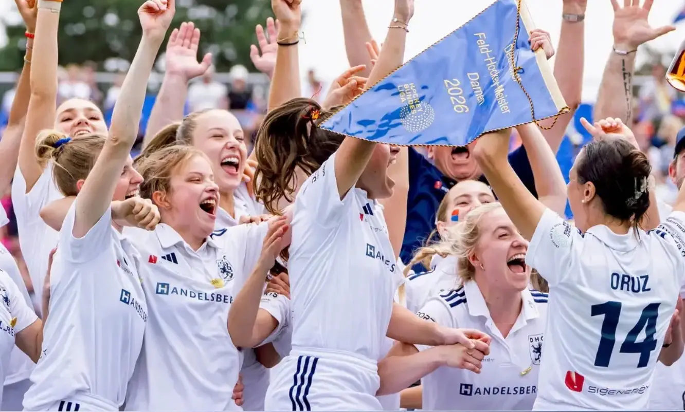 Women's team celebrating the 2026 German field hockey championship with the pennant